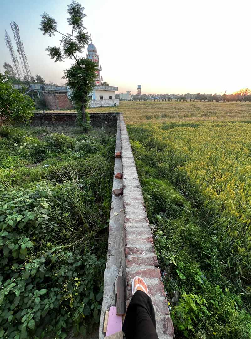 Piede di donna che sta seduta su un muretto di un giardino indiano